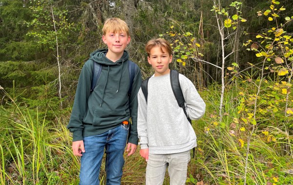 To gutter med sekker står i en skog